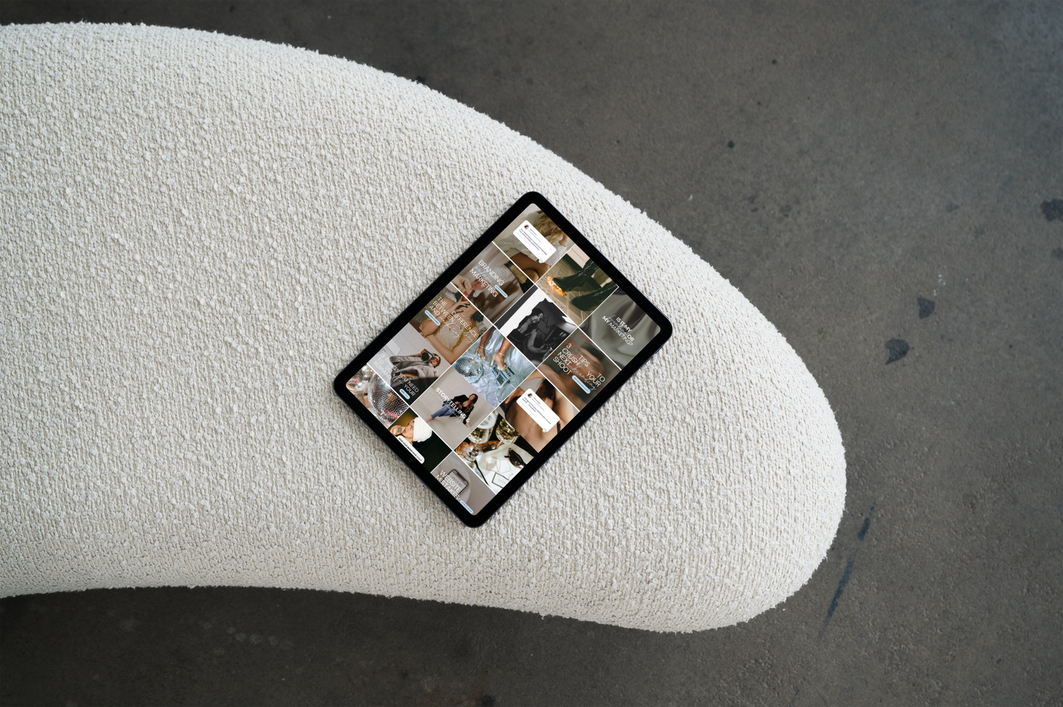 Tablet resting on a cream bouclé chair showing a managed social media grid